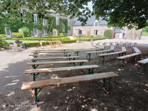 Outdoor reception setup at Manoir de la Bégaudière in Mont-Dol with picnic tables and stone buildings