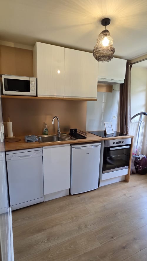 Modern kitchen in Le Duguay Trouin apartment at Manoir de la Bégaudière, Mont-Dol with white cabinetry, wooden counters, and