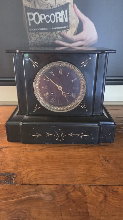 Ornate black mantelpiece clock with Roman numerals in Le Duguay Trouin apartment at Manoir de la Bégaudière, Mont-Dol