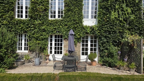 Ivy-covered courtyard at Manoir de la Bégaudière in Mont-Dol with seating area and umbrella