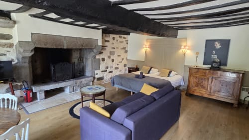 Le Duguay Trouin apartment at Manoir de la Bégaudière with fireplace, purple sofa, and bed in Mont-Dol