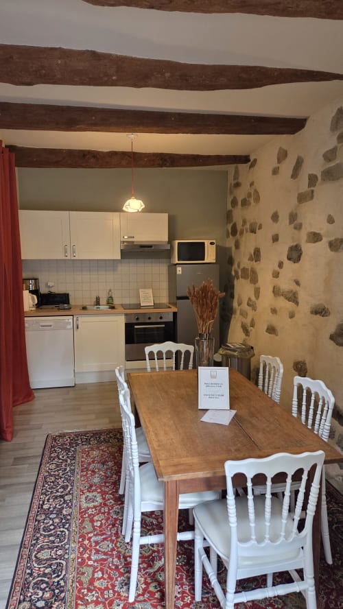 Dining area in Le Marion Dufresne at Manoir de la Bégaudière, Mont-Dol, with wooden table, white chairs, exposed beams, and