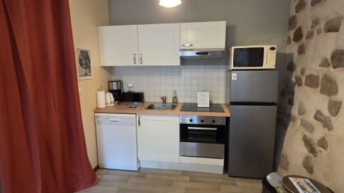 Modern kitchenette in Le Marion Dufresne apartment at Manoir de la Bégaudière, Mont-Dol, with stainless steel appliances and