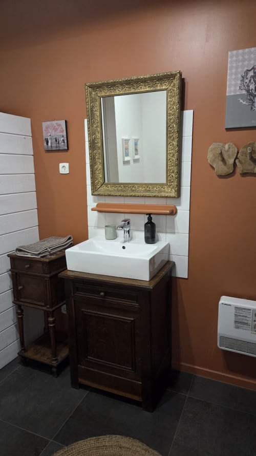 Elegant bathroom vanity with white sink, gold-framed mirror, and dark wood cabinet at Manoir de la Bégaudière in Mont-Dol