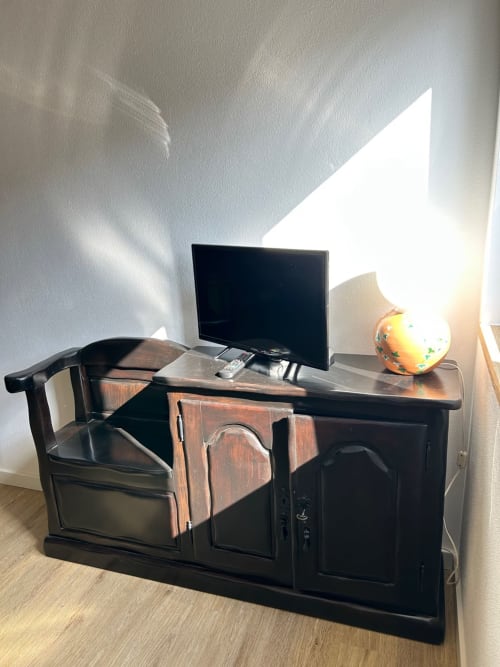Escrivaninha de madeira escura com TV de tela plana e luminária decorativa na Casa das Rodas, em Casas do Sinhel