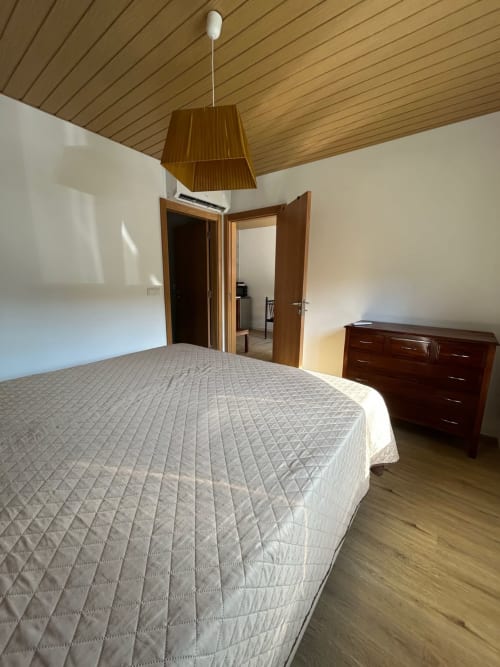 Quarto espaçoso da pousada Casa das Rodas em Alvares com cama de casal, cômoda de madeira e comodidades modernas