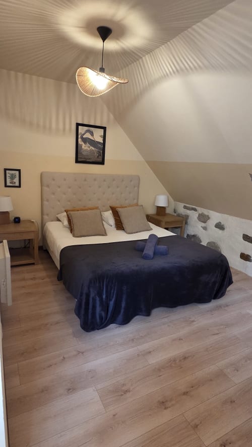Cozy bedroom in Le Marion Dufresne at Manoir de la Bégaudière with bed, pendant light, wooden floors