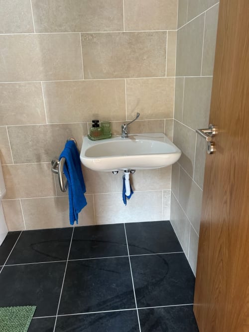 Moderno lavatório com azulejos bege e piso preto na casa de hóspedes Casas do Sinhel em Alvares, Portugal