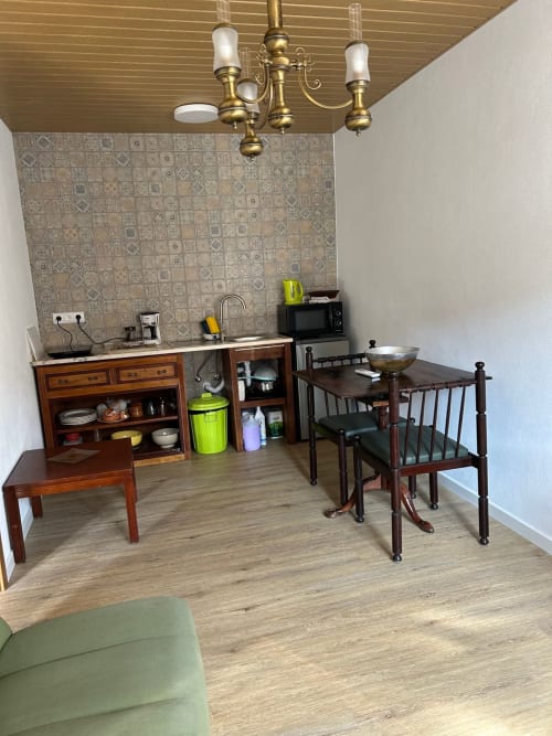 Cozinha e sala de jantar da Casa das Rodas com móveis de madeira, painel com padrões, lustre em latão e moderno