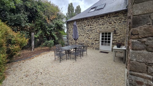 Stone cottage patio at Manoir de la Bégaudière in Mont-Dol with dining table, umbrella, and garden views