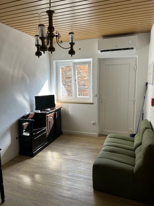 Sala de estar moderna na Casa das Rodas em Alvares com sofá verde, TV e vistas para a montanha