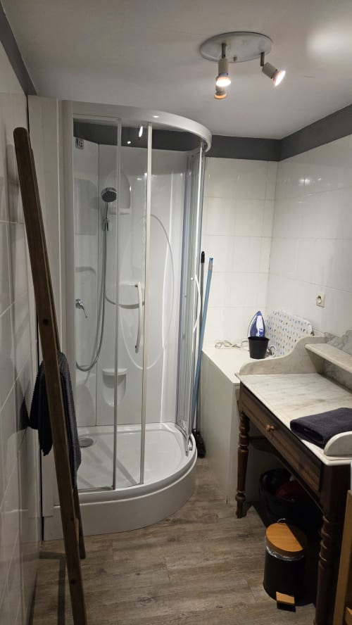 Modern bathroom with curved glass shower enclosure, double sink vanity, and overhead lighting at Manoir de la Bégaudière in