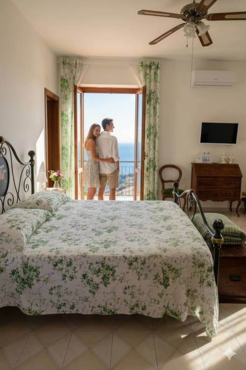 Coppia che ammira la vista sul mare dal balcone della camera da letto del Pupi Catania B&B, Aci Castello con biancheria floreale