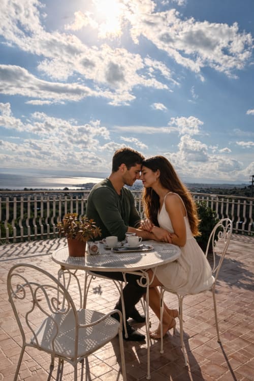 Coppia che gusta il caffè in terrazza con vista mare a Pupi Catania, Aci Castello, affacciati sulla costa