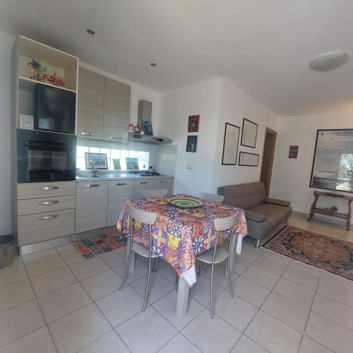Cucina moderna e zona living della cottage famiglia Sciara presso Pupi Catania B&B, Aci Castello con tavolo da pranzo e divano