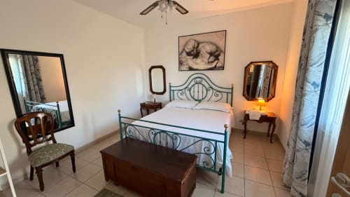 Camera Sciara al Pupi Catania B&B con letto in ferro, mobili in legno e vista sul giardino ad Aci Castello