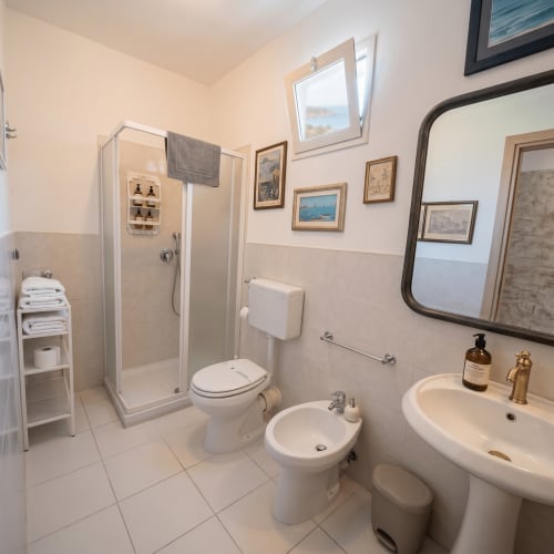 Bagno luminoso con doccia, wc, bidet e lavabo a colonna presso Pupi Catania Etna Farm B&B ad Aci Castello