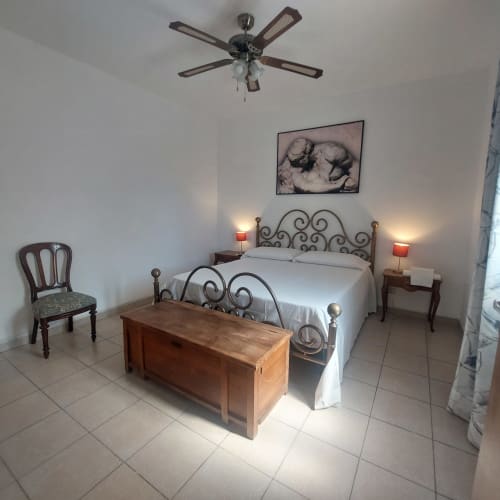 Camera luminosa nella casetta Sciara di Pupi Catania B&B, Aci Castello con letto in ferro battuto e ventilatore a soffitto