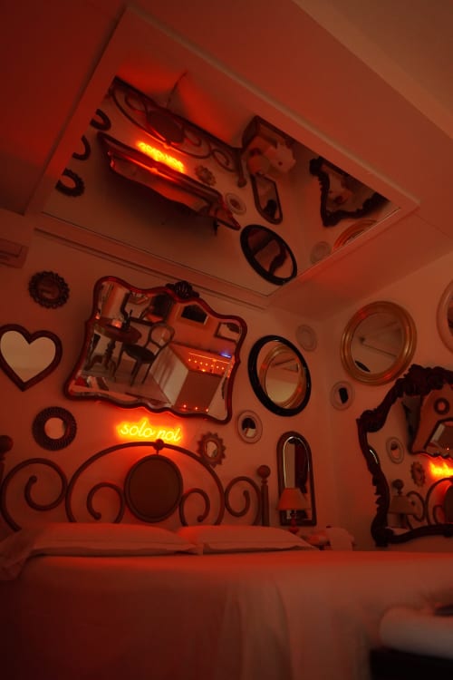 Stanza illuminata da neon rossi presso Pupi Catania B&B, con specchi decorativi e insegne luminose che creano un'atmosfera accogliente