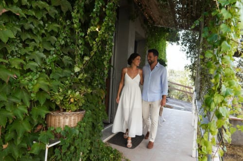Coppia che passeggia attraverso l'ingresso lussureggiante ricoperto di edera verso la casa colonica Pupi Catania Etna Farm B&B ad Aci Castello, Sicilia