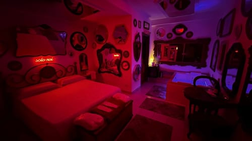 Camera da letto moderna con illuminazione neon rossa e viola, letto, TV e minibar presso Pupi Catania Etna Farm B&B ad Aci Castello