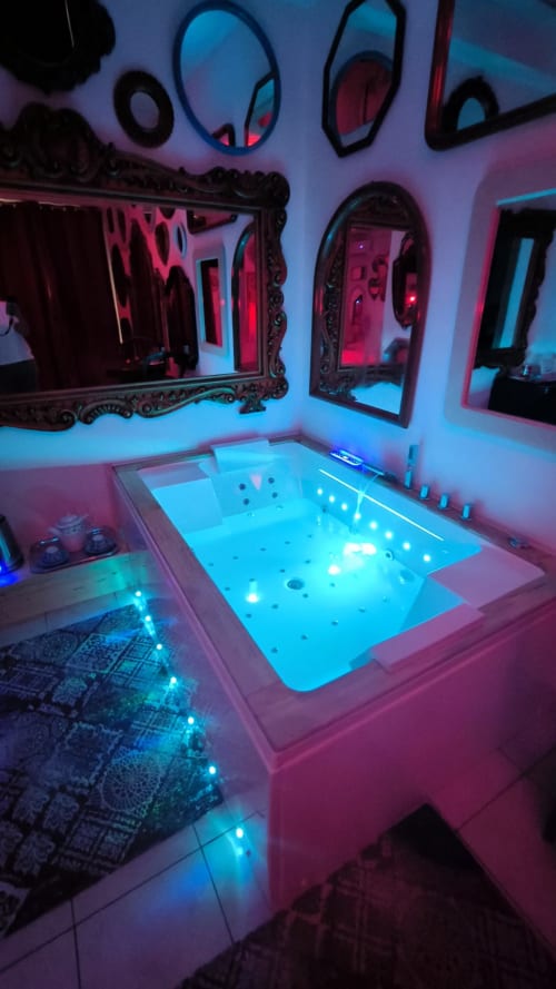 Moderna sala idromassaggio con vasca spa illuminata, specchi decorati e illuminazione blu neon presso il Pupi Catania B&B in Sicilia