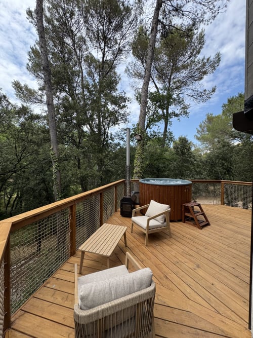 Terrasse en bois du Domaine d'Olga avec bain à remous, transats et grands pins, Aniane