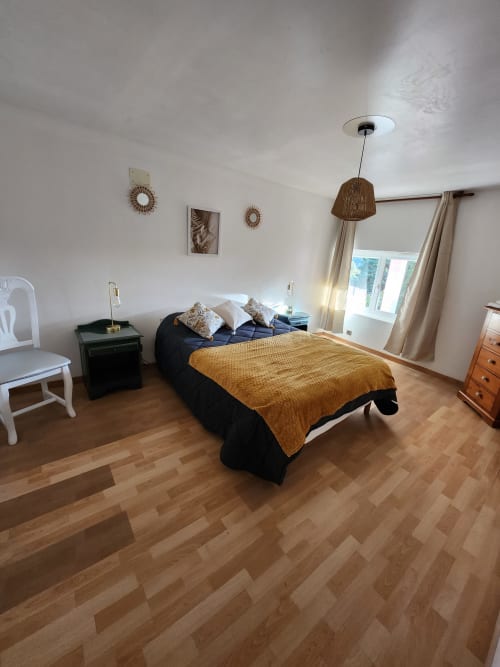Chambre lumineuse à Domaine De Poulharies avec lit queen-size, parquets en bois et vue sur le jardin