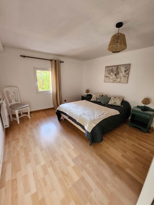 Chambre spacieuse à la Domaine De Poulharies à Carcassonne avec parquet, lit noir et lumière naturelle