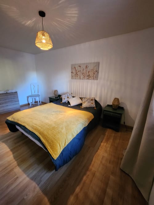 Chambre cosy du Domaine De Poulharies à Carcassonne avec literie jaune, luminaire suspendu et décoration moderne