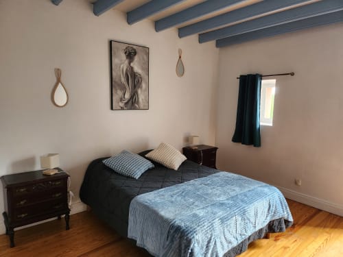 Bedroom at Domaine De Poulharies, Carcassonne with bed, wooden beams, dark curtains, and framed artwork