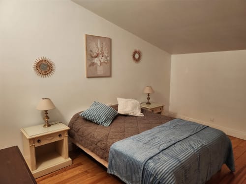Cozy bedroom at Domaine De Poulharies B&B in Carcassonne with bed, wooden nightstands, and vintage wall decor