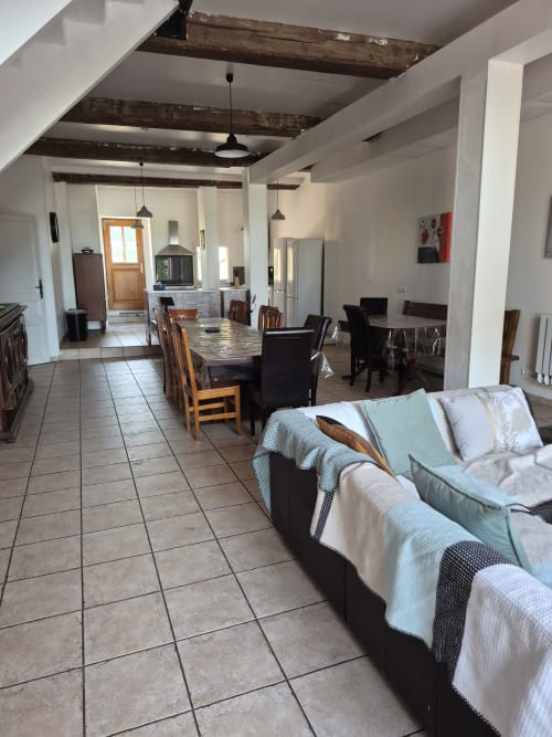 Open-plan living area at Domaine De Poulharies B&B in Carcassonne with dining table, sofa, and exposed wooden beams