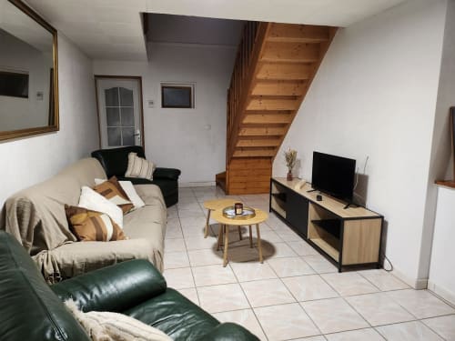 Salon chaleureux du Domaine De Poulharies B&B à Carcassonne avec canapé, téléviseur et escalier en bois