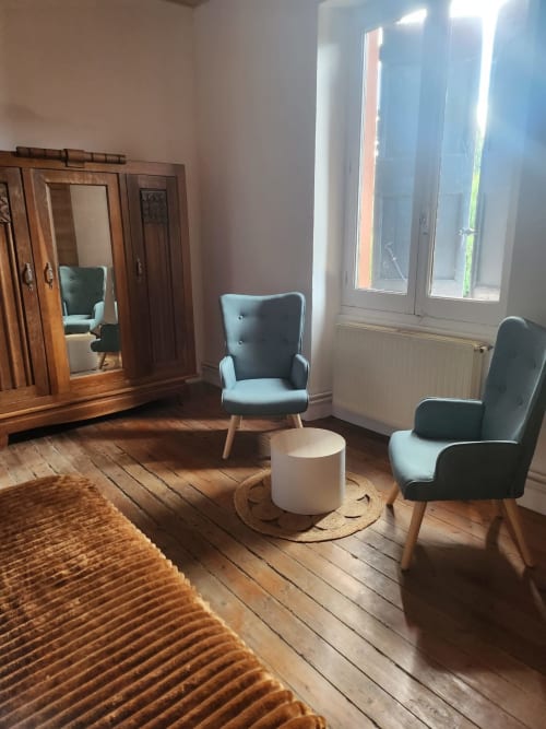 Salon du gîte Blanquette au Domaine De Poulharies à Carcassonne avec fauteuils bleus, armoire en bois et lumière naturelle