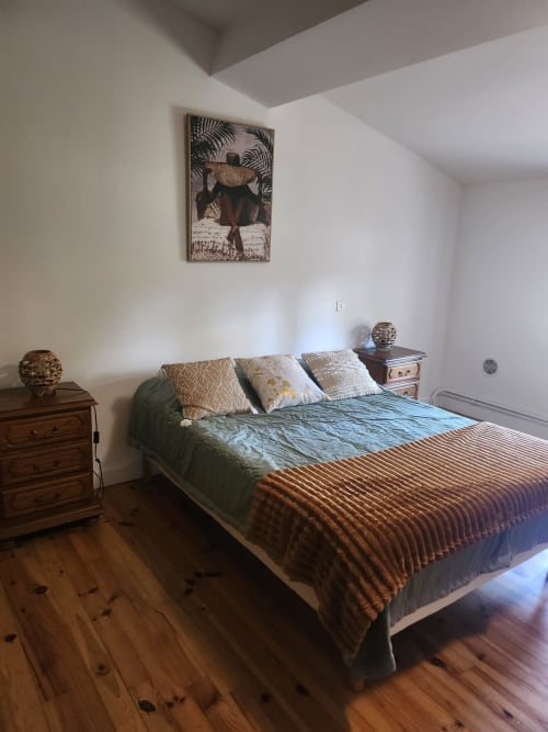 Chambre Blanquette au Domaine De Poulharies à Carcassonne : lit, tables de nuit en bois et décoration tropicale