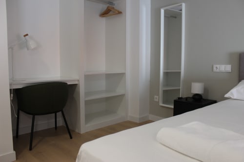 Moderno estudio en Palacio Mambrilla de Valladolid con escritorio, silla, estanterías, espejo y cama