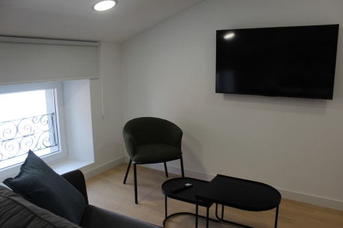 Apartamento estudio moderno en Palacio Mambrilla Valladolid con TV mural, silla negra, mesa y vistas al balcón