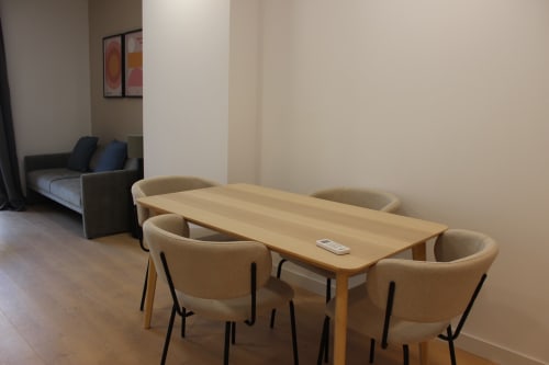 Moderno apartamento estudio en Palacio Mambrilla, Valladolid, con mesa de comedor de madera, sillas beige y área de cama visible