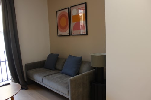 Moderna sala de estar en Palacio Mambrilla con sofá gris, cojines azules y arte mural geométrico en apartamento de Valladolid