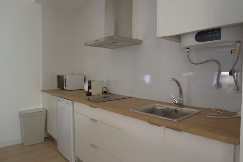 Cocina moderna en apartamento Palacio Mambrilla, Valladolid, con armarios blancos, encimera de madera y fregadero de acero inoxidable