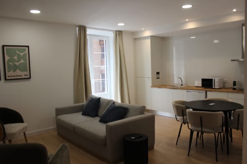 Salón del apartamento de 2 dormitorios en Palacio Mambrilla, Valladolid, con sofá, mesa de comedor, cocina y vistas a la ciudad