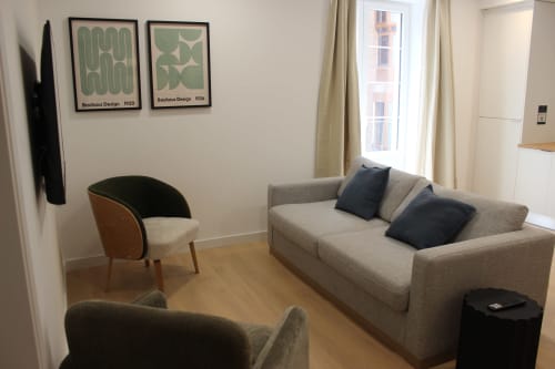 Salón moderno del apartamento Palacio Mambrilla Valladolid con sofá beige, sillón auxiliar y vistas a la ciudad