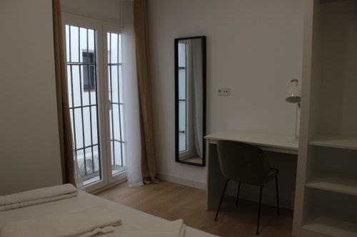 Dormitorio moderno con escritorio, silla y puertas de cristal en el hotel Palacio Mambrilla de Valladolid