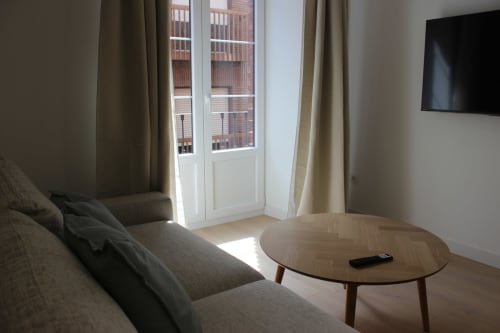 Sala de estar moderna en Palacio Mambrilla, Valladolid con cómoda zona de descanso, mesa redonda de madera y vistas a la ciudad