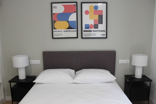 Recámara moderna en Palacio Mambrilla con cabecera oscura, ropa de cama blanca, cuadros Bauhaus y lámparas de mesa contemporáneas