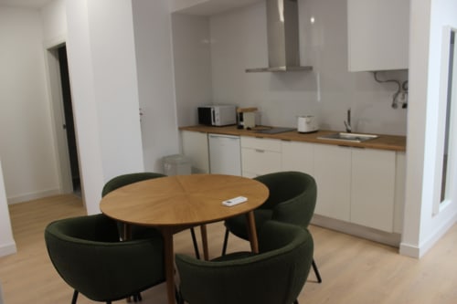 Cocina y comedor modernos en el apartamento Palacio Mambrilla, Valladolid, con mesa de madera redonda y sillas verdes