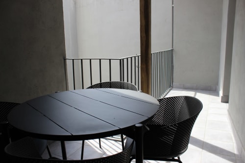 Soleada terraza con mesa de comedor negra y sillas en el apartamento Palacio Mambrilla de Valladolid