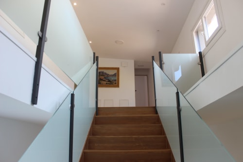Escalera moderna con barandillas de cristal en el apartamento Palacio Mambrilla de Valladolid