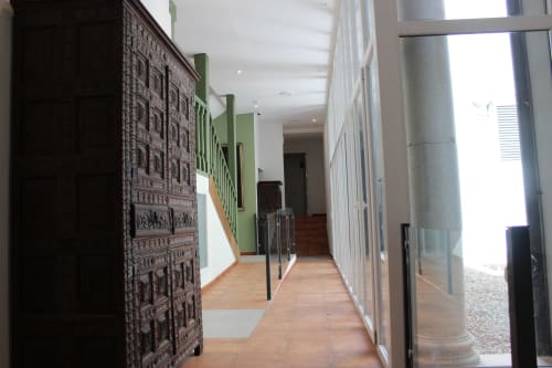 Pasillo del Palacio Mambrilla en Valladolid con suelo de madera, paredes con acentos verdes y barandillas metálicas modernas